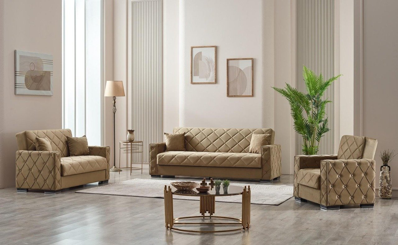 Modern living room with beige quilted furniture, a glass coffee table with golden legs, and abstract wall art.