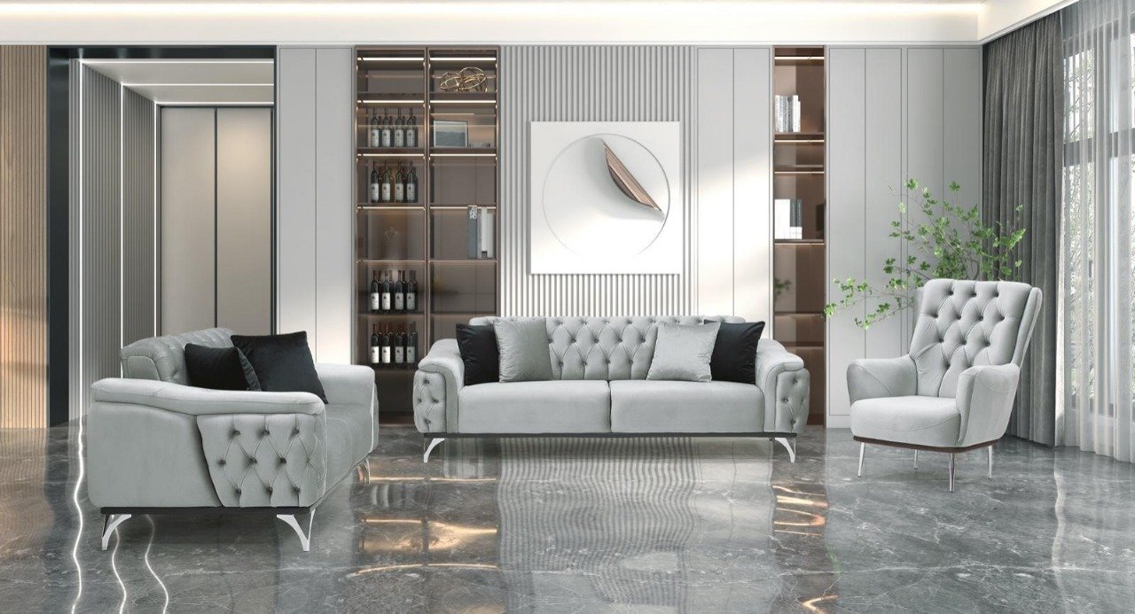Modern living room with tufted gray sofas, a glass shelving unit with wine bottles, abstract wall art, and marble flooring.