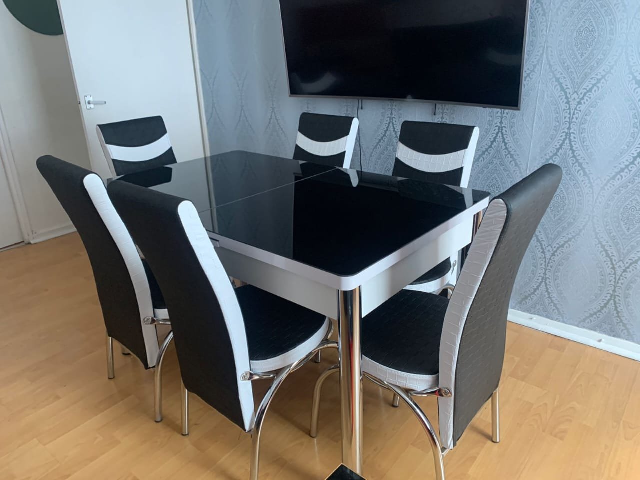 Modern ClearSpan Dining Set with a black glass table and six black and white chairs.