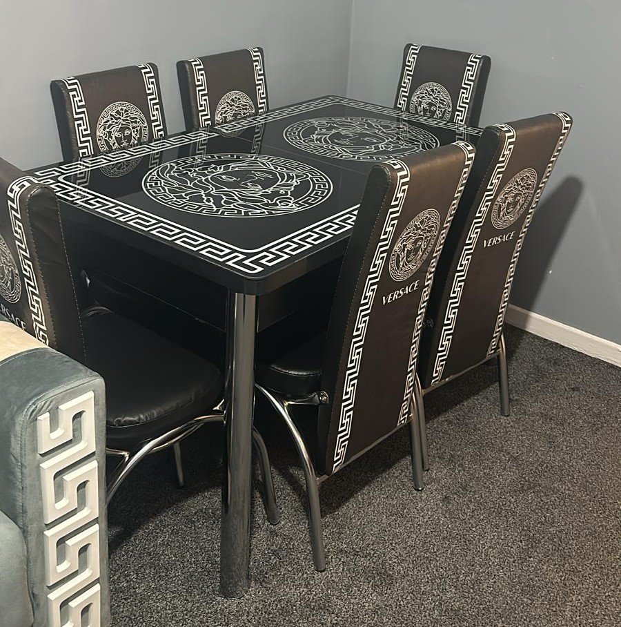 Elevra Glass Dining Table with black and white Greek key and Medusa designs, surrounded by six matching chairs.