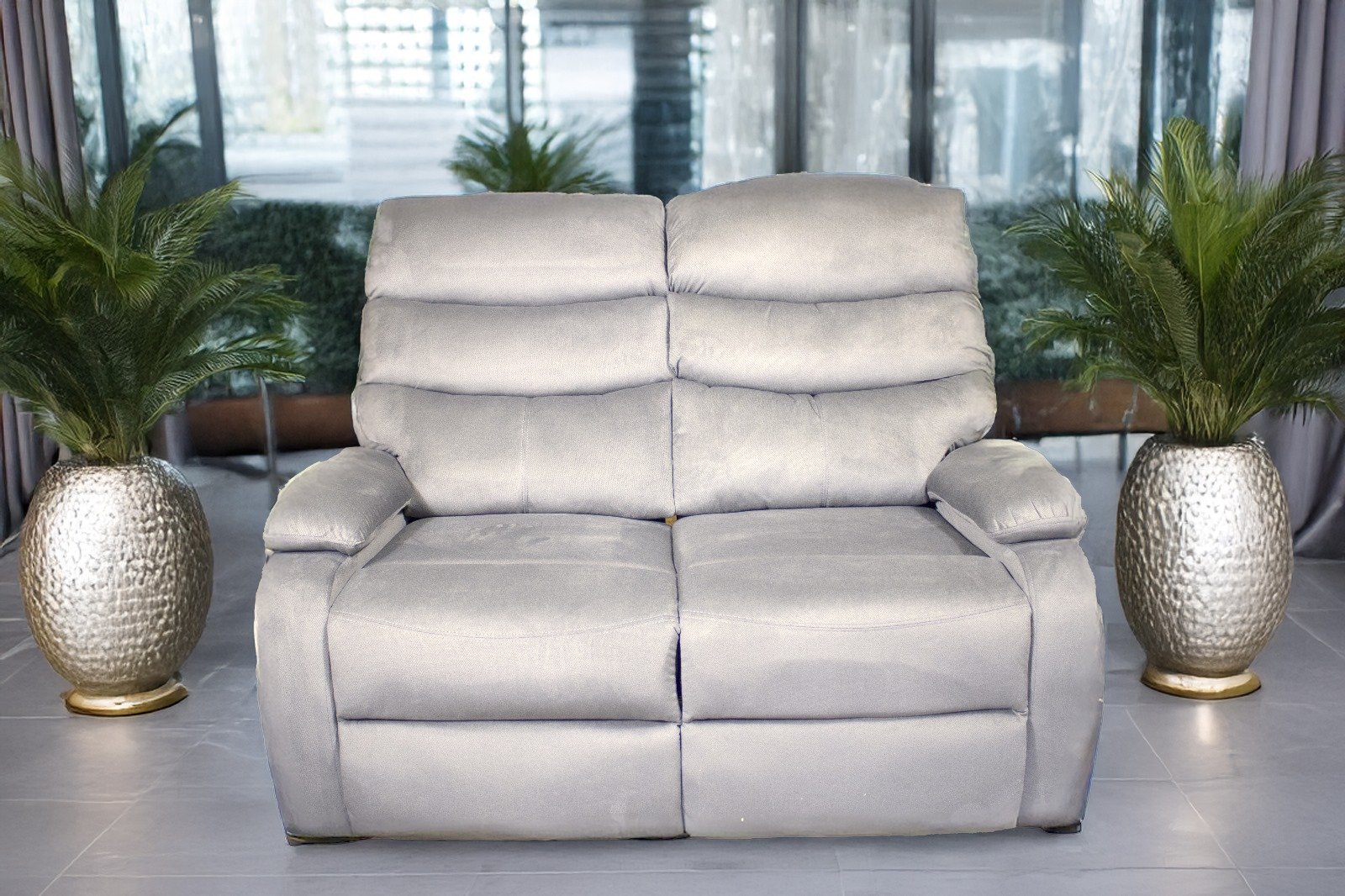 Light gray two-seater sofa with green potted plants on either side.