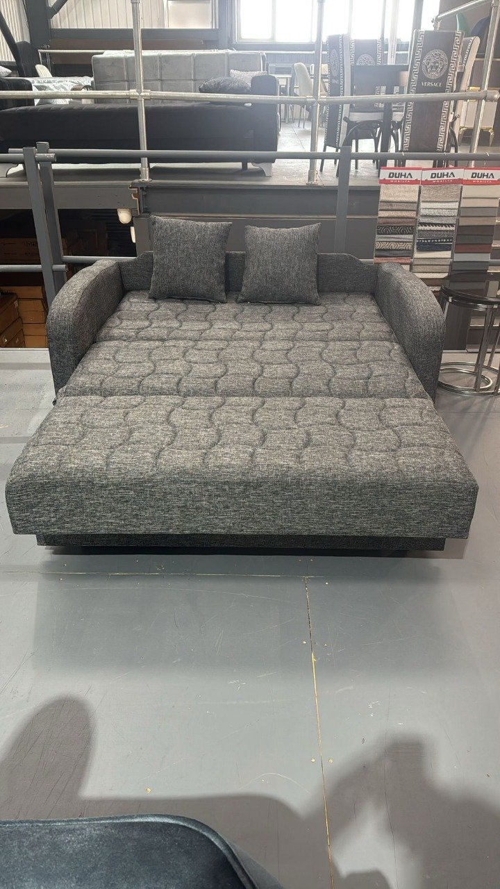 Luna Loft Love Seat in a showroom with quilted gray fabric and two pillows.