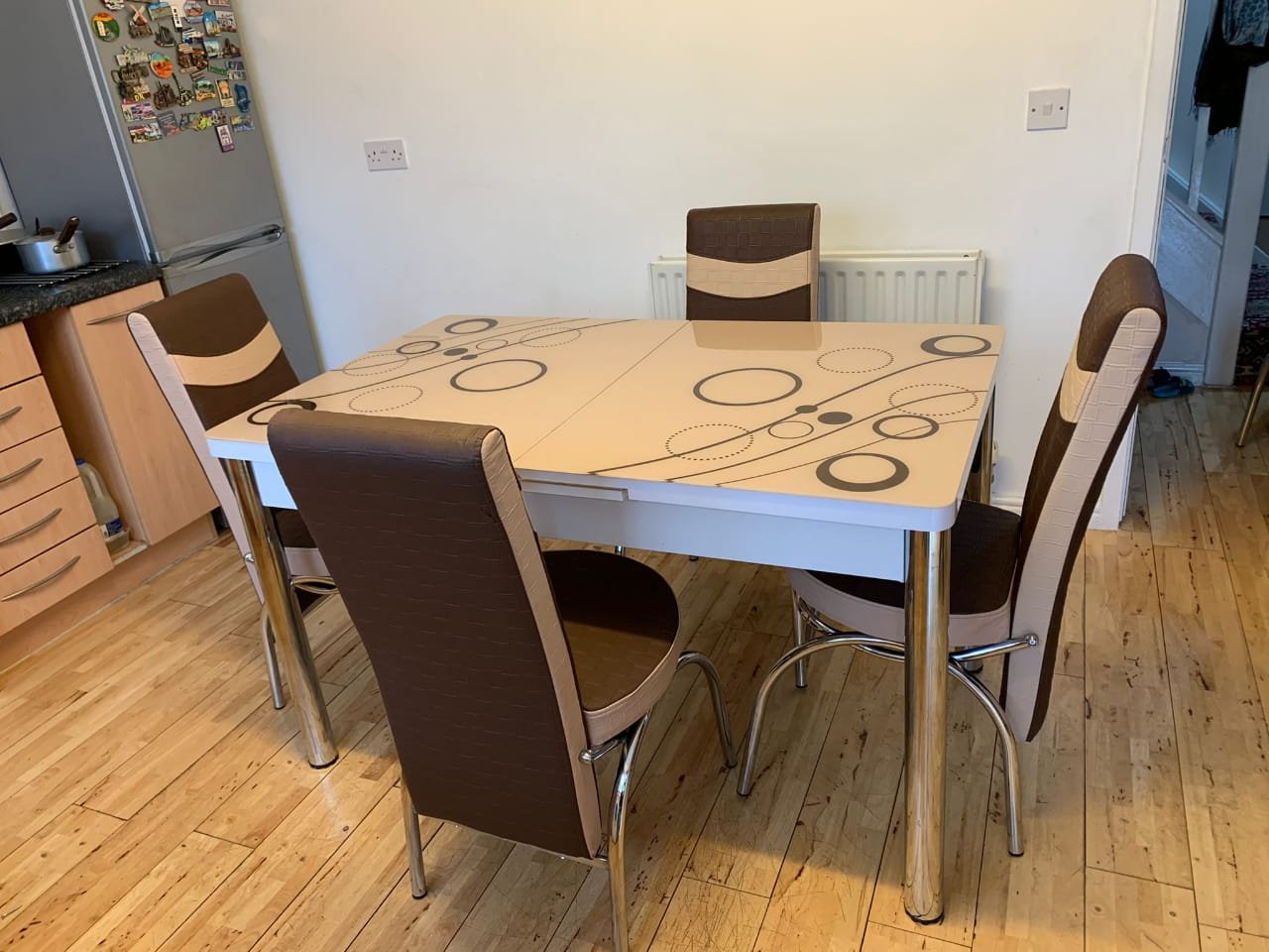 OptraGlass Extendable Table with circular patterns and four chairs in a dining area.