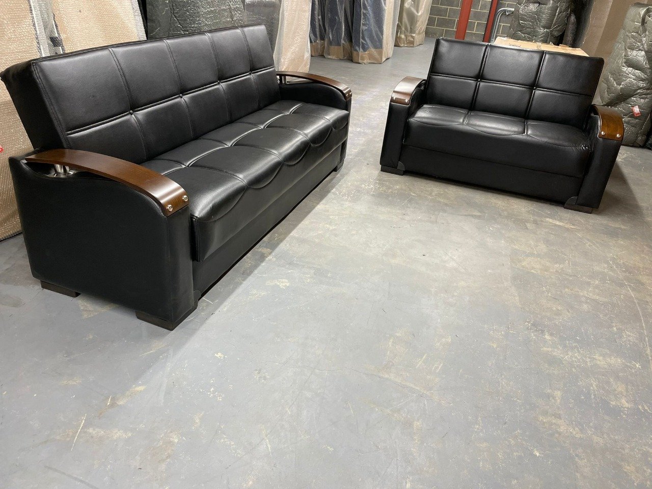 Raven Luxe Sofa Bed and matching loveseat in black leather with dark wood armrests.